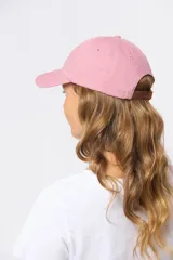 Gorro con visera de lona rosado con bordado frontal en tonos verde y violeta.