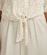 Blusa color crema con estampado animal print de jaguar en tonos dorados, escote en V, mangas 3/4 y nudo en la parte inferior.