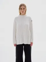 Buzo tejido de punto color beige, con cuello subido, diseño oversized y aberturas laterales en el ruedo.