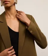 Blazer oversize color verde oliva, con solapas en el cuello y doble abotonadura delantera.