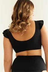 Top de bikini negro con volados en los hombros y nudo regulable en el escote.