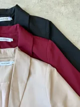 Blazer sastrero de corte recto y estructura clásica, confeccionado en tela tipo gabardina. Presenta solapas tradicionales, hombreras marcadas y bolsillos laterales con solapa.