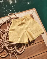 Short de lino a rayas blancas y amarillas, con cintura elastizada y lazo ajustable en el frente.