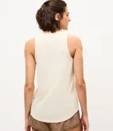 Musculosa deportiva Get Over en microfibra ligera texturizada de color marfil, con cuello redondo, tirantes anchos y bajo redondeado.