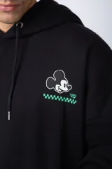Buzo tipo canguro color negro con capucha y cordones ajustables. Presenta un pequeño estampado en el pecho con la silueta de Mickey Mouse y un detalle a cuadros en color verde.