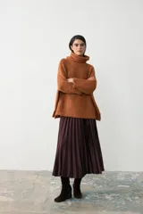 Sweater tipo poncho de tejido de punto grueso en color ocre, con cuello alto holgado y diseño de corte amplio con aberturas laterales en el ruedo.