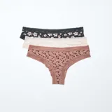 Pack de tres tangas de microfibra con detalles de encaje en la cintura y los bordes. El conjunto incluye una tanga negra con estampado floral, una tanga lisa en tono nude y una tanga marrón con estampado de flores pequeñas.