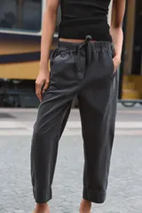 Pantalón de tiro bajo con cintura elástica ajustable mediante cordón, bolsillos delanteros y bolsillos de plastrón en la parte trasera.