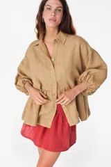 Camisa de lino italiano color beige, de silueta holgada, con corte fruncido en la cintura y mangas voluminosas con puños elásticos.