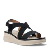Sandalias de plataforma con tiras cruzadas negras, una de ellas con textura cuadriculada, y cierre de velcro en el talón. La base es de color beige con diseño texturizado.
