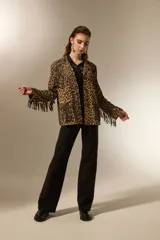 Blazer de poliéster con estampado animal print de leopardo, diseño holgado, cuello solapa, cierre frontal con botones y flecos decorativos en el pecho y la espalda. Incluye bolsillos frontales.