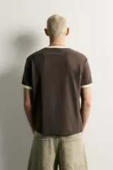 Camiseta regular fit gris melange con cuello redondo y mangas cortas. Presenta acabados con rib en contraste de color marrón oscuro en el cuello y los puños.
