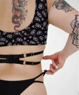 Top negro con estampado de flores blancas, breteles anchos y tiras cruzadas en el abdomen.