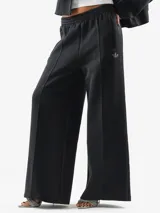 Pantalón deportivo Adidas de corte holgado y pernera ancha, color negro, con cintura elástica y cordón ajustable. Cuenta con bolsillos laterales y el logo del trifolio bordado en la pierna izquierda.
