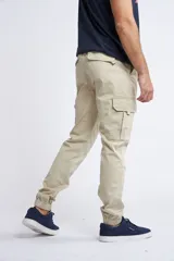 Pantalón cargo color beige de corte slim, con cintura elástica y cordón de ajuste. Presenta bolsillos laterales tipo cargo y puños elásticos en los tobillos.