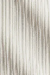 Remera ajustada de punto acanalado suave, color blanco, con cuello redondo ribeteado en picot y tapeta de botones. Es de manga larga.