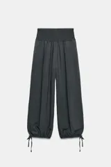 Pantalón baggy de tiro medio color rosado, con cintura elástica fruncida tipo nido de abeja y bajos ajustables con cordones.