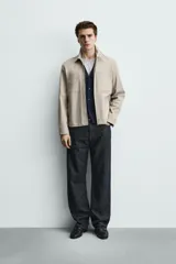 Sobrecamisa negra de corte relajado, confeccionada en tejido con mezcla de algodón elástico. Presenta cuello solapa, cierre frontal de cremallera, bolsillos de plastrón en el pecho y bolsillos de vivo en la cadera.