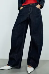 Jeans de tiro alto confeccionados en denim azul oscuro, con diseño barrel de pernera holgada que se estrecha hacia los tobillos. Cuenta con cinco bolsillos, trabillas para cinto y cierre frontal con cremallera y botón.