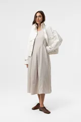 Campera de denim liviano oversize color blanco, con cuello alto, cierre frontal con botones y bolsillos delanteros con solapa. Presenta pespuntes en contraste y una silueta relajada.