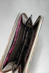 Billetera de cuero natural con diseño pintado a mano, cierre perimetral y múltiples compartimentos interiores.