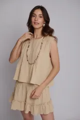 Falda corta de muselina de algodón color beige, con diseño de alforzas verticales, cintura elástica y ruedo con volado.