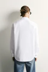 Camisa slim fit de Zara confeccionada en tejido de algodón con textura estructurada, cuello clásico con solapa y manga larga con puños abotonados. Cierre frontal con botonadura.