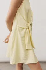 Vestido corto blanco sin mangas, con cuello redondo y detalle de nudo drapeado en el lateral.