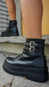 Borcegos negros de cuero sintético con plataforma y cordones. Presentan una tira con apliques metálicos alrededor del tobillo y cierre lateral con cremallera.