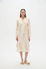 Vestido midi holgado de viscosa color beige, con mangas largas, cuello mao, cierre frontal con botones y detalle de bordado con lurex con diseño de hojas doradas.
