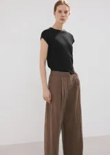 Pantalón de corte recto y tiro regular, color marrón, con bolsillos laterales y traseros con ribete. Cierre frontal con cremallera, botón y ganchos ocultos.