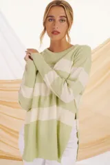 Sweater de punto color verde claro con rayas horizontales anchas color crema, de corte holgado y mangas largas.