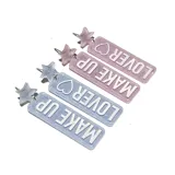 Aros colgantes con forma rectangular con glitter y la leyenda "Make Up" en uno y "Lover" en el otro.