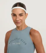 Musculosa deportiva Get Over de microfibra color celeste, con cuello redondo y diseño sin mangas. Presenta un estampado frontal con la inscripción "ATHLETIC CLUB est. 1990".