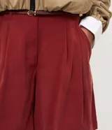 Short femenino Marfinno de modelaje suelto y caída liviana, color verde militar, con cintura con pasadores, pinzas frontales, bolsillos laterales y bajo recto. Incluye un cinturón fino de rafia con hebilla metálica.