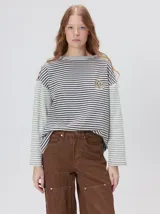 Remera de manga larga con diseño a rayas horizontales en tonos celestes y blancos en el cuerpo, y mangas a rayas azul marino y blancas. Presenta cuello redondo en color azul marino, logo bordado en el pecho y calce holgado.