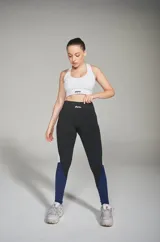 Calza deportiva larga de tiro alto, color negro con recortes laterales en blanco y azul.