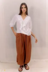 Camisa blanca de algodón con escote en V, volados delanteros con detalles de encaje y mangas largas con puños fruncidos.