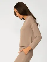 Buzo de punto color rosa, con cuello redondo y detalle de tejido crochet en el escote. Presenta mangas largas y un corte clásico con caída suave.