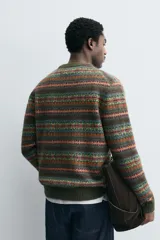 Jersey de punto con diseño jacquard geométrico de rayas horizontales en tonos tierra, verde y naranja. Presenta cuello redondo, manga larga y terminaciones en rib acanalado.