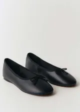 Zapato tipo bailarina de cuero vacuno color negro, con punta redonda y detalle de lazo decorativo en la parte frontal.