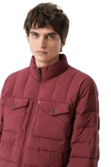 Campera puffer acolchada color bordó, con cierre frontal, cuello alto y dos bolsillos frontales con solapa y botón a presión.