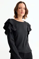 Remera de manga larga color crudo, confeccionada en tejido acanalado, con detalle de volados en los hombros y cuello redondo.