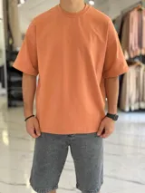 Remera oversize de algodón pesado en color naranja salmón, con cuello redondo y mangas cortas.
