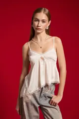 Musculosa de satén color blanco, con breteles finos regulables, escote en V decorado con detalles de encaje y diseño fluido.