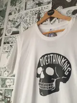 Remera blanca de algodón con estampado de una calavera negra con la palabra "Overthinking" en la parte superior.