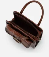 Cartera pequeña de mano con diseño estructurado, confeccionada en poliuretano color marrón con acabado envejecido. Cuenta con tapa frontal decorada con una hebilla metálica, cierre principal con cremallera, asa de mano rígida y correa larga ajustable y desmontable.