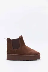 Bota corta de gamuza color tostado, tipo botineta, con paneles elásticos laterales y suela de plataforma plana.