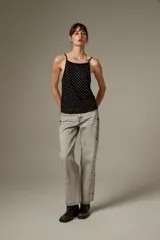Top halter negro de viscosa, sin mangas, con tirantes finos y cobertura completa de ojalillos metálicos plateados.