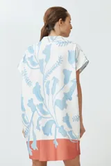 Túnica corta color blanco con estampado floral celeste y base color salmón.